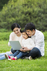 Happy family using laptop on the grass