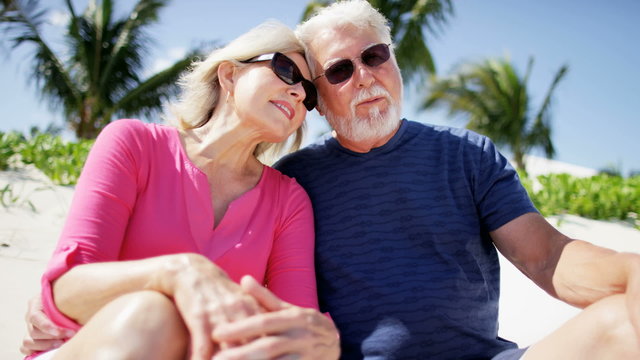 Retired Caucasian couple smiling for social media at a beach resort