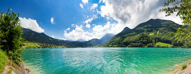 Panoramic image from the shore of a Green and Blue Mountain lake in the Swiss Alps