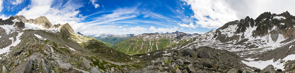 360 degree panorama taken in the mountains on top of the Furkapass in the Swiss Alps on a sunny day with a beautiful cloudscape