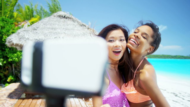 Young multi ethnic girlfriends wearing bikini taking selfie on beach
