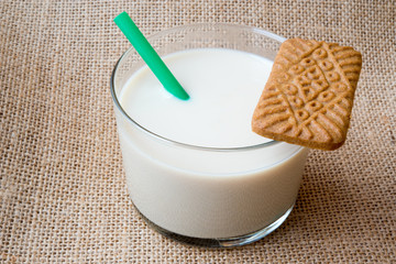 Glass of milk with straw and cookie.