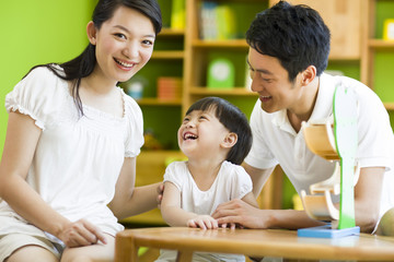 Young family playing toy slide