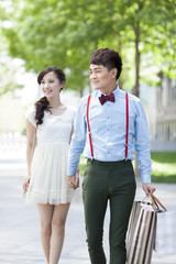 Stylish young couple walking with shopping bags in hand