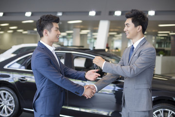 Young businessman buying car in showroom