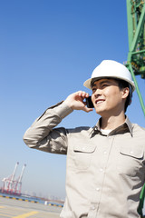 Male shipping industry worker on the phone with shipping dock background