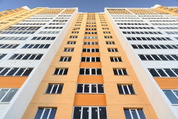 New building apartments painted orange on clear blue sky