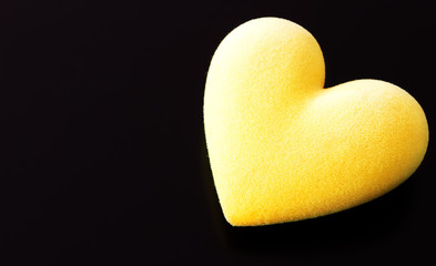 Fototapeta premium Yellow fluffy heart on a black background with a place for the text