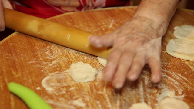 women's hands rolled dough for dumplings; close-up