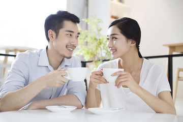Happy young couple drinking coffee in coffee shop