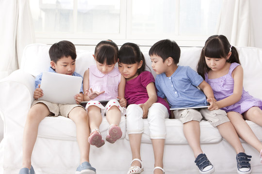 Children playing digital tablet at home