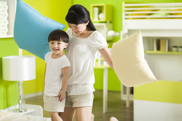 Happy mother and daughter having a pillow fight
