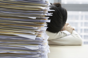 Businesswoman Sleeping Next To Pile Of Work
