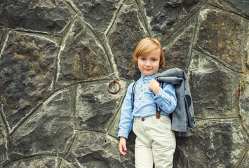 Vintage fashion portrait of a cute little blond kid boy, young boy posing outdoors