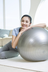 Fototapeta premium Happy young woman leaning on fitness ball