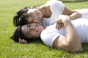 Young couple lying in grass, outdoors