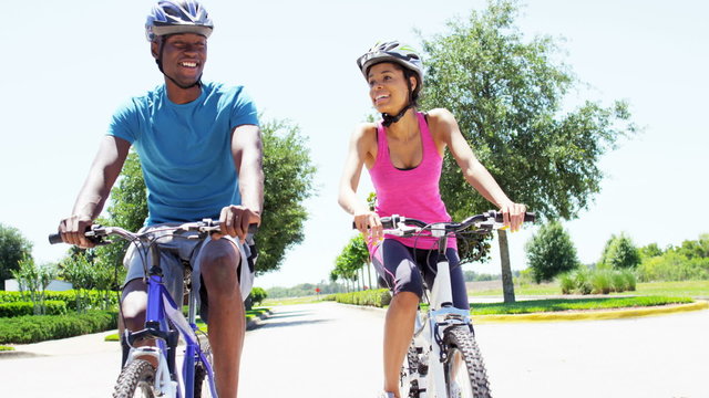Young active African American guy and girl cycling to keep healthy outdoors