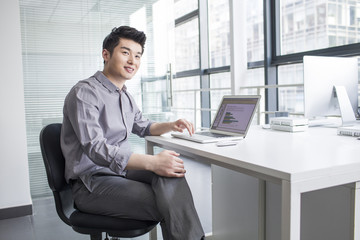 Young businessman using laptop in office