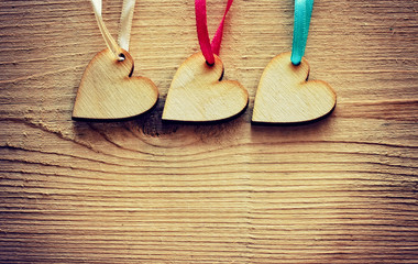 three plywood hearts hang on ribbons