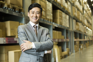 Fototapeta premium Confident businessman arms crossed in warehouse