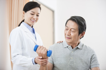 Senior patient exercising with dumbbell under doctor's help