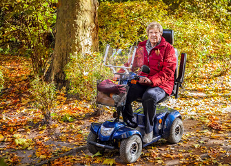 Seniorin mit Elektromobil im Herbstwald
