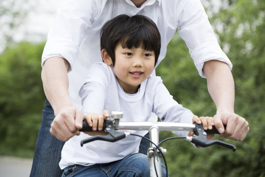 Father teaching son to ride a bicycle