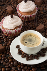 Chocolate cupcakes and cup of espresso on the coffee beans 