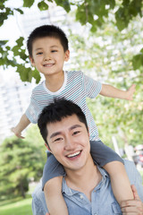 Little boy sitting on his father's shoulders with arms outstretched