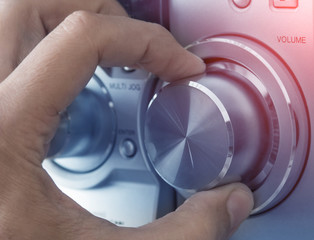 Hand adjusting volume control. Tinted image.