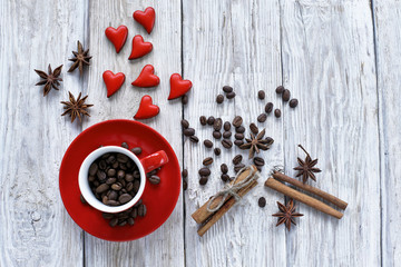 Red cup with coffee beans  and red hearts on wooden background 