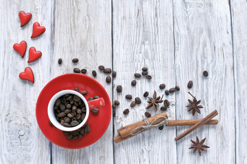 Red cup with coffee beans  and red hearts on wooden background 