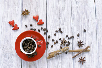 Red cup with coffee beans  and red hearts on wooden background 