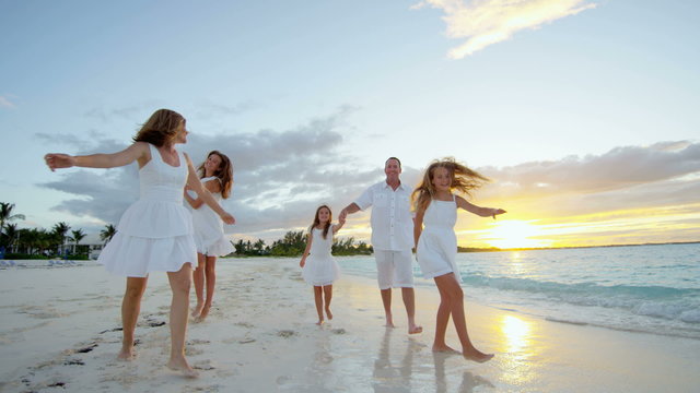 Caucasian family walking barefoot on beach together at sunset