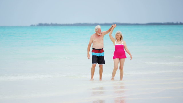 Mature Caucasian couple in swimwear dancing together on tropical beach 