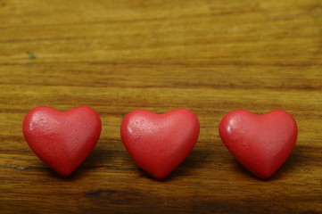 Three red heart on wooden background