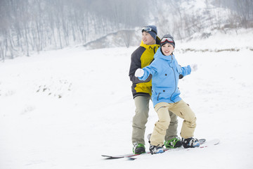 Fototapeta na wymiar Young man teaching girlfriend to snowboard