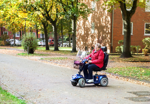 Seniorin mit Elektromobil wendet auf der Stra&szlig;e und l&auml;chelt 