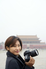 Portrait of a young woman holding camera, Tiananmen Square, Beijing, China