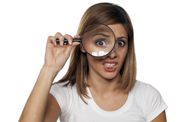unhappy young woman looking through a magnifying glass
