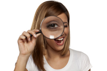 smiling young woman looking through a magnifying glass