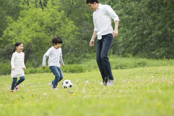Naklejka premium Happy father and children playing football together