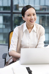 Businesswoman sitting with a laptop and a notebook