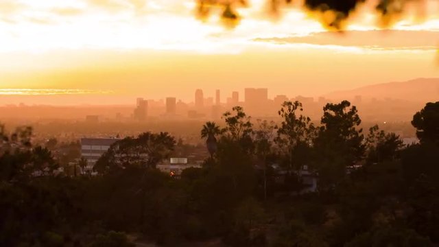 Pan to view of Hollywood, Los Angeles, California, at sunset with orange sky and hazy skyline.  Recorded in 4K, ultra high definition.