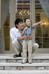 Father and son having fun in front of house