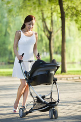 Obraz premium Young woman taking a walk with her baby in pram