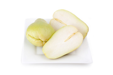 Chayote Squash on a White Plate – A whole chayote squash, and one cut in half on a white plate.