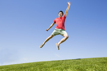 Fototapeta na wymiar Cheerful young man jumping on grass
