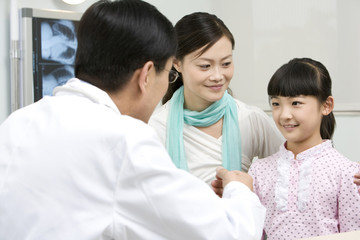 Obraz premium Doctor speaking with his young patient and her mother