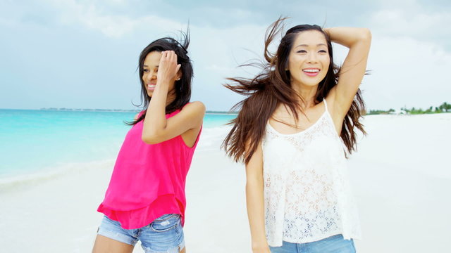 Happy multi ethnic carefree girlfriends on ocean beach sand 